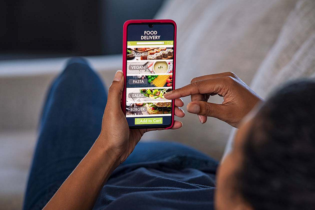Person ordering food online through a delivery app on a smartphone.